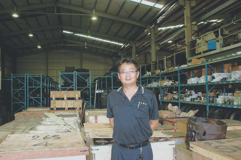 ●黑上傳動總經理龔祖望,其周邊為堆滿皮帶輪的公司倉儲。圖/黑上提供 image
